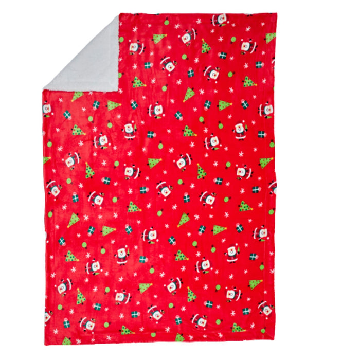 A red fleece blanket with a festive Christmas pattern featuring Santa Claus, green Christmas trees, and white snowflakes, with a light gray reverse side shown at the corner.