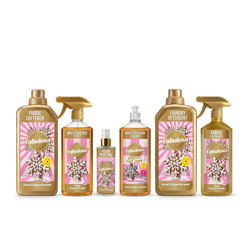 A Fabulosa holiday scent product lineup in a single-serve dispenser and six larger bottles, including fabric softener, multi-surface cleaner, direct flame retardant, laundry detergent, and fabric softener, all in gold packaging with pink and white labels on a white background.