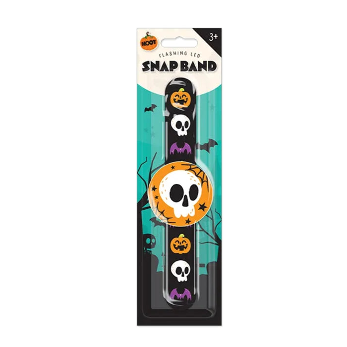 Halloween-themed snap band with a black base decorated with skull and pumpkin motifs, packaged in a retail card with a teal and white background.