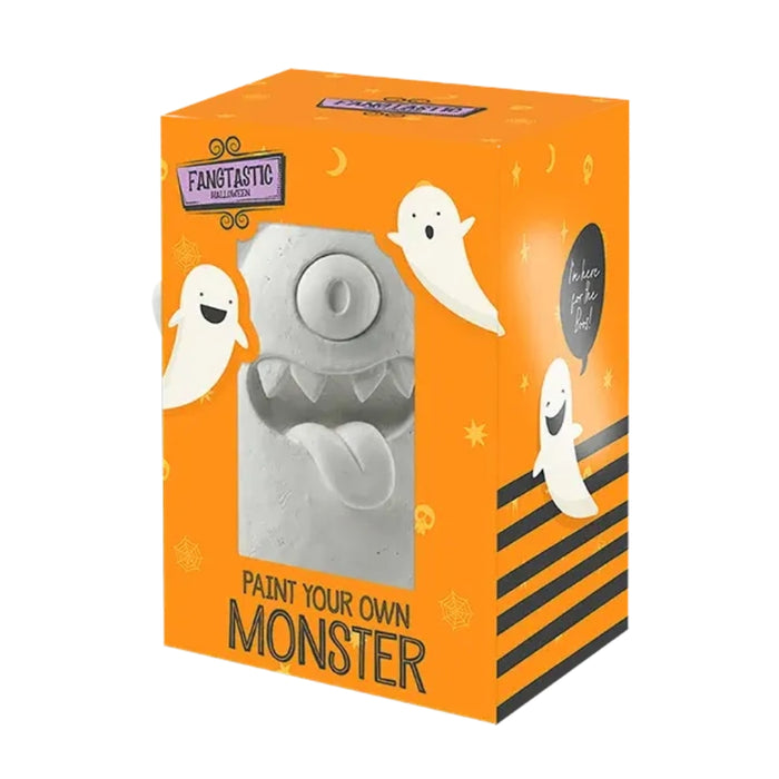An orange retail box for a Halloween-themed craft product. The front shows a gray unpainted monster face visible through a window, with ghost illustrations, the text 'PAINT YOUR OWN MONSTER,' and a visible 'Fangtastic' logo.